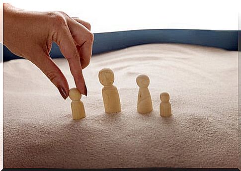 Hand placing wooden figures in the sand symbolizing how to avoid aggressive conversation