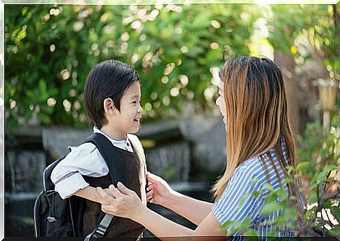 Boy with backpack talking to his mother about school