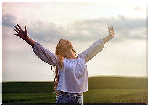 Woman with open arms outdoors to represent the philosophy of keledén